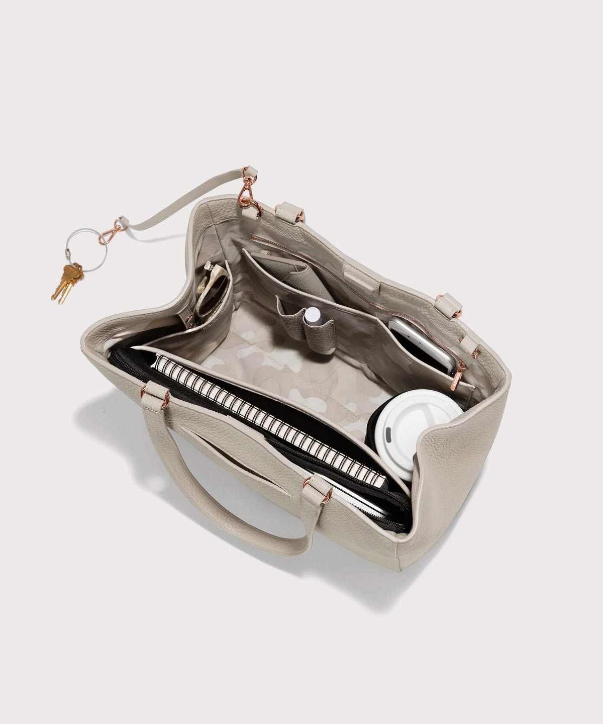 Dagne Dover medium Allyn Tote in light grey with objects inside the interior pockets.
