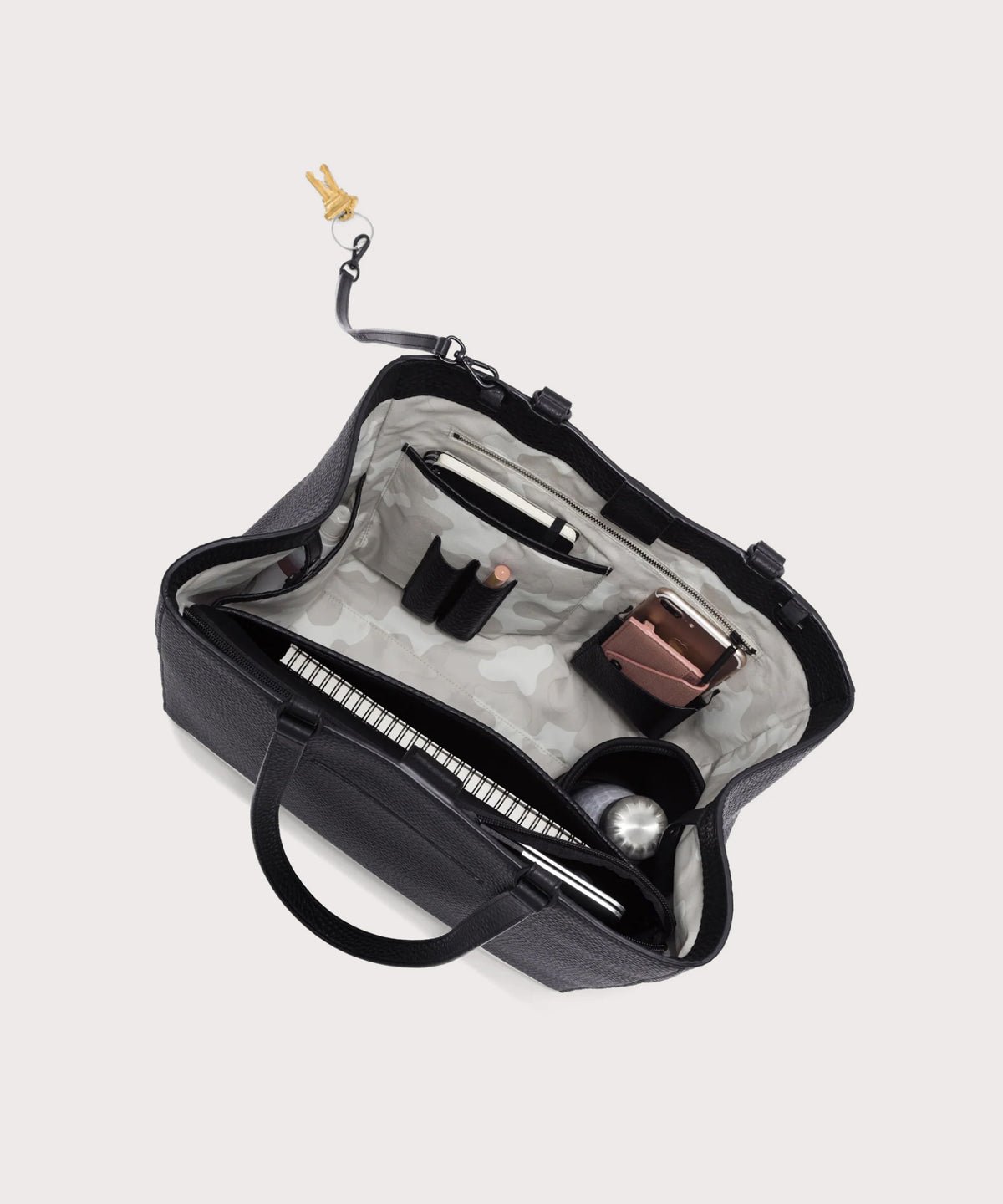 Dagne Dover large Allyn Tote in black with objects inside the interior pockets.
