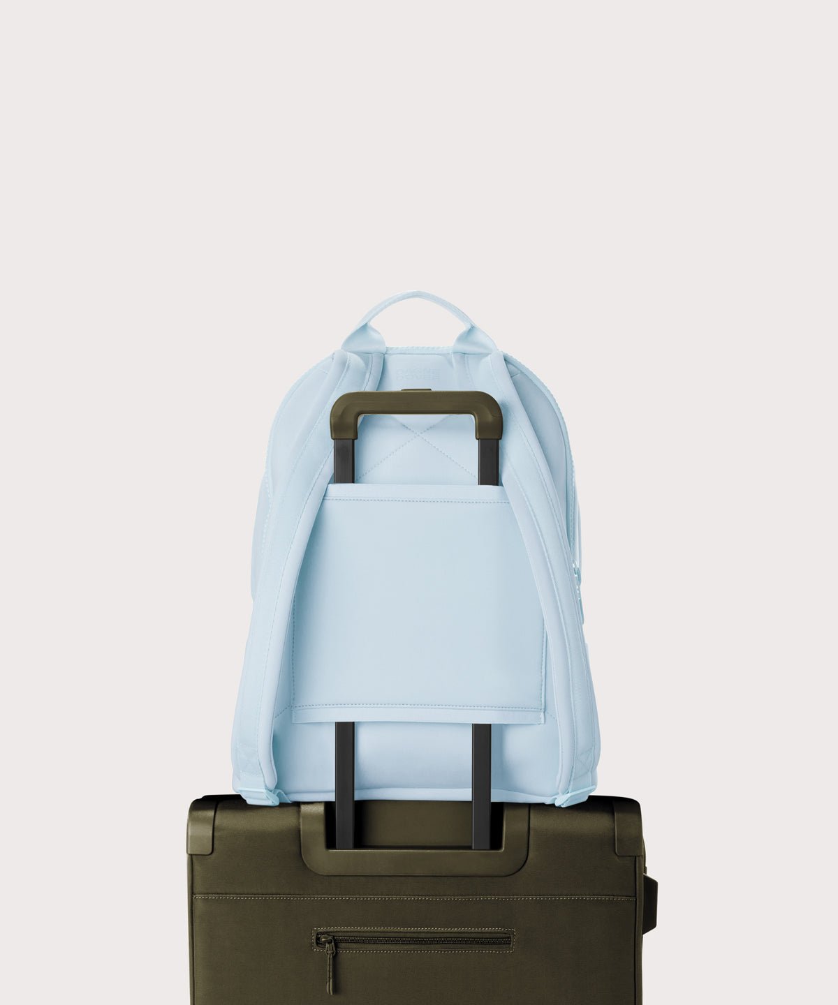 Dagne Dover large Dakota Neoprene Backpack in an airy, lighter sky blue strapped to luggage with the neoprene luggage-handle sleeve.
