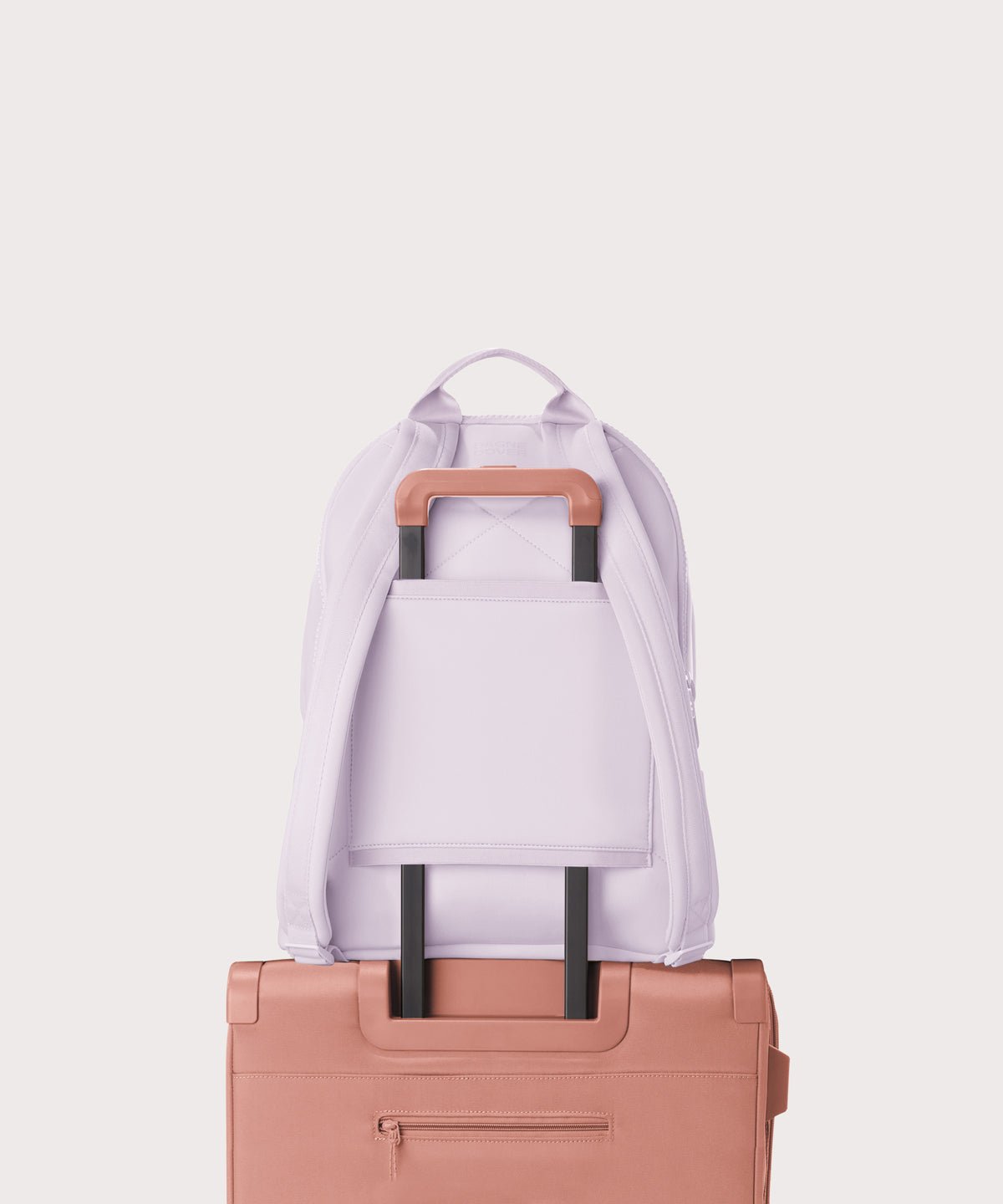 Dagne Dover large Dakota Neoprene Backpack in A soft purple with grey undertones strapped to luggage with the neoprene luggage-handle sleeve.
