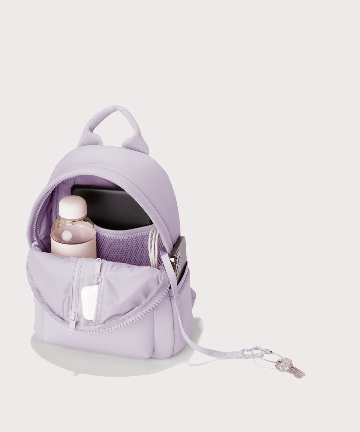 Dagne Dover Dakota Small Neoprene Backpack in a soft purple with grey undertones seen from an angle. unzipped, revealing the interior air mesh pockets.