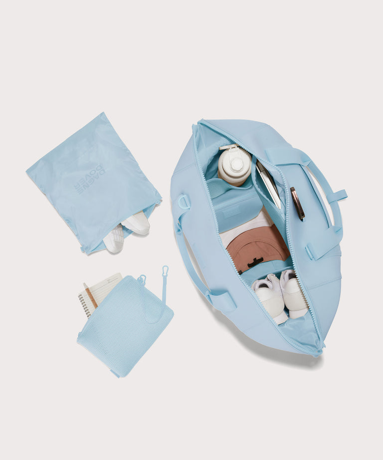 Extra large Landon Carryall in an airy, lighter sky blue unzipped, top down view. 
