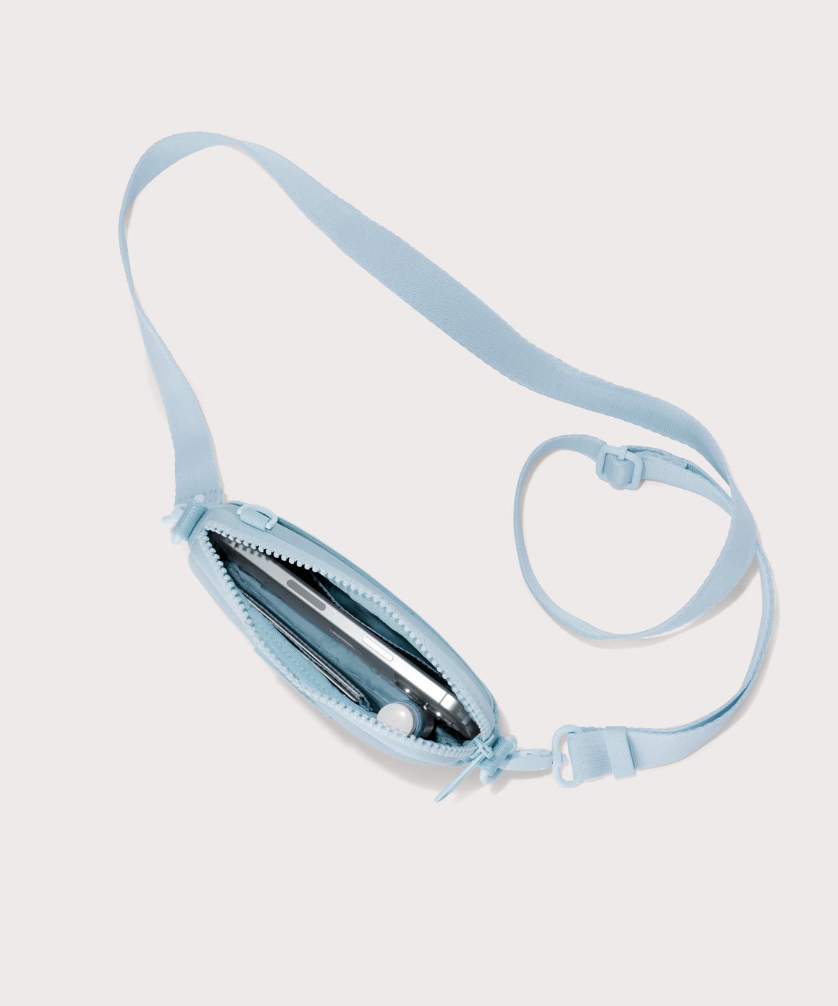 Dagne Dover Mara Phone Sling unzipped in an airy, lighter sky blue. seen from above, exposing the interior card slots.
