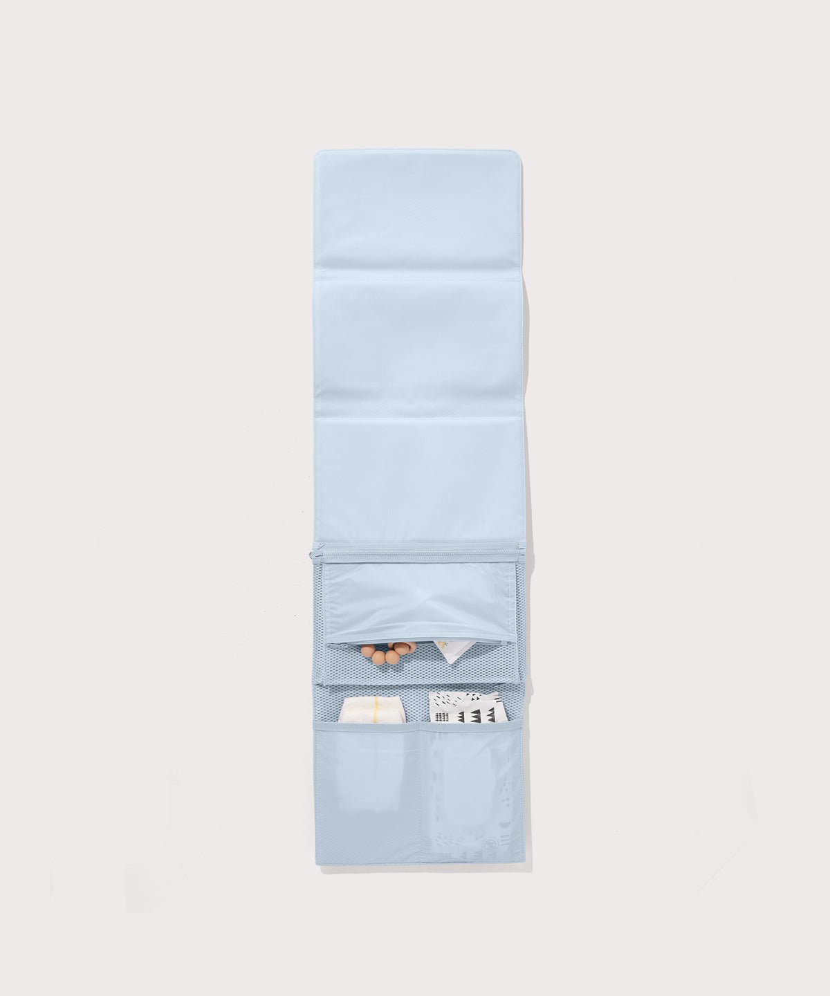 Dagne Dover Joey Changing Kit in an airy, lighter sky blue unfolded, revealing the interior zipper pocket and interior slip pockets.
