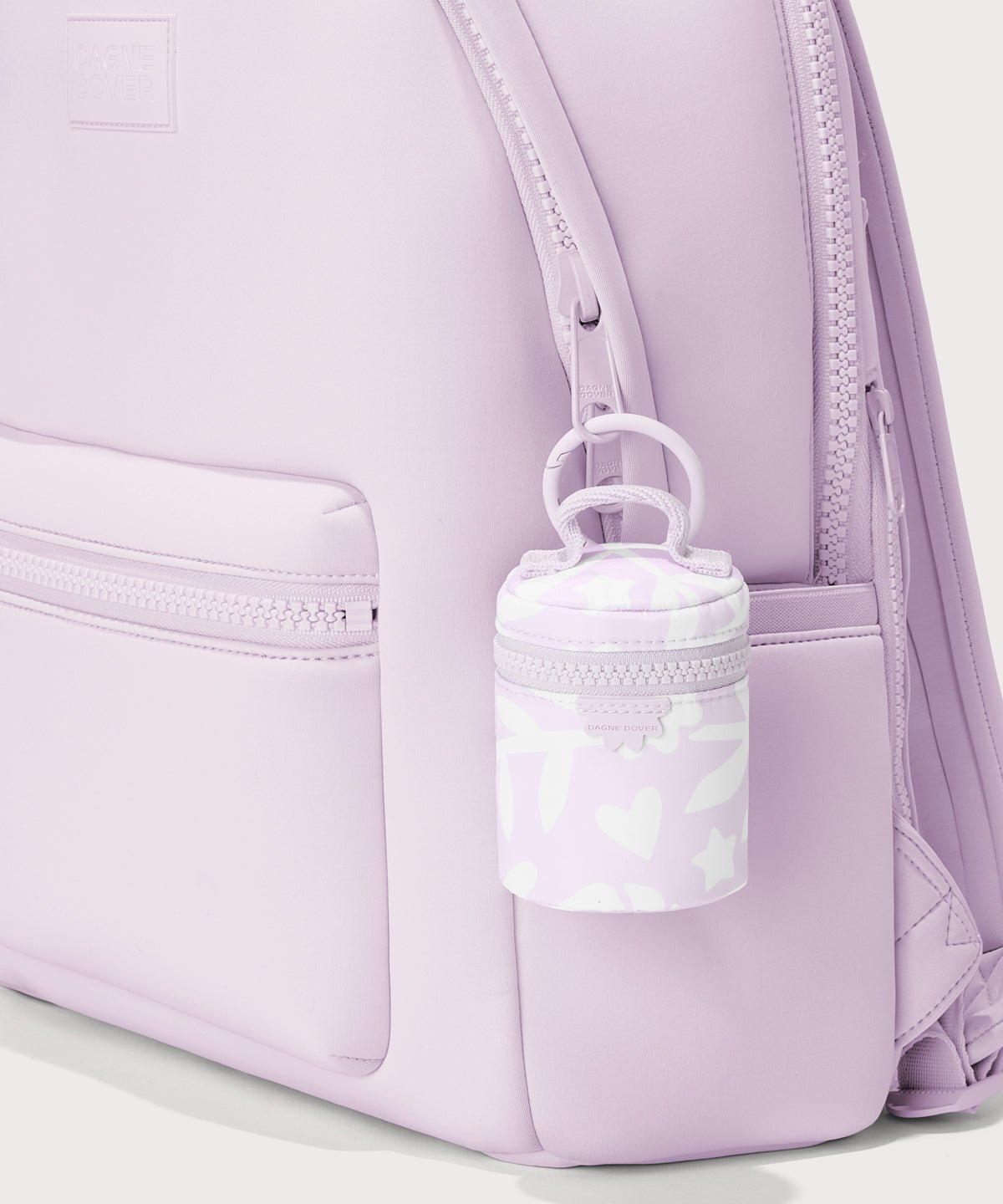 Dagne Dover Mila Keychain in a washed lilac and cream floral print seen on a backpack.

