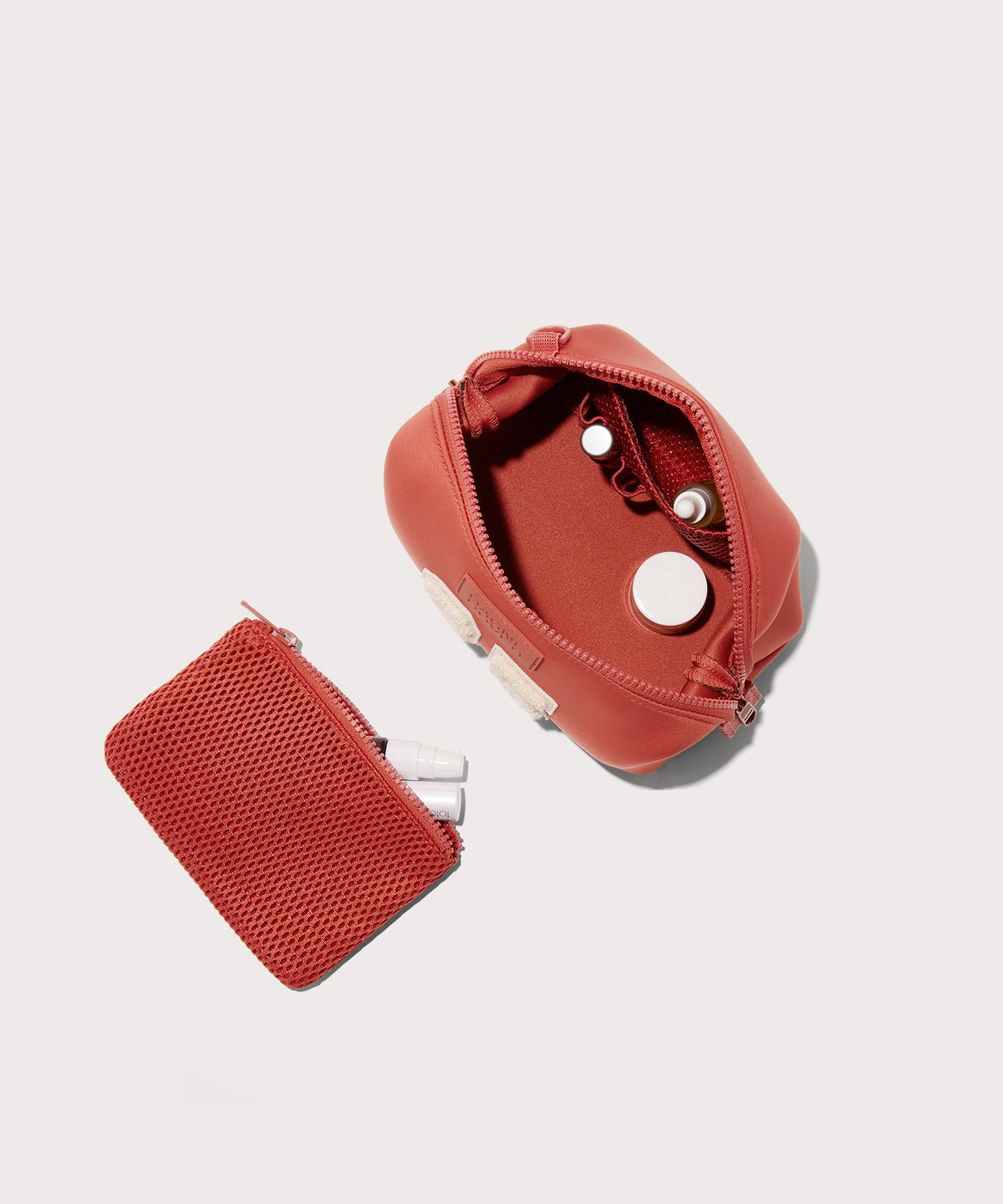 Dagne Dover Small Hunter Toiletry Bag in a poppy, vintage wash red unzipped and seen from above with the removable air mesh pouch alongside it.