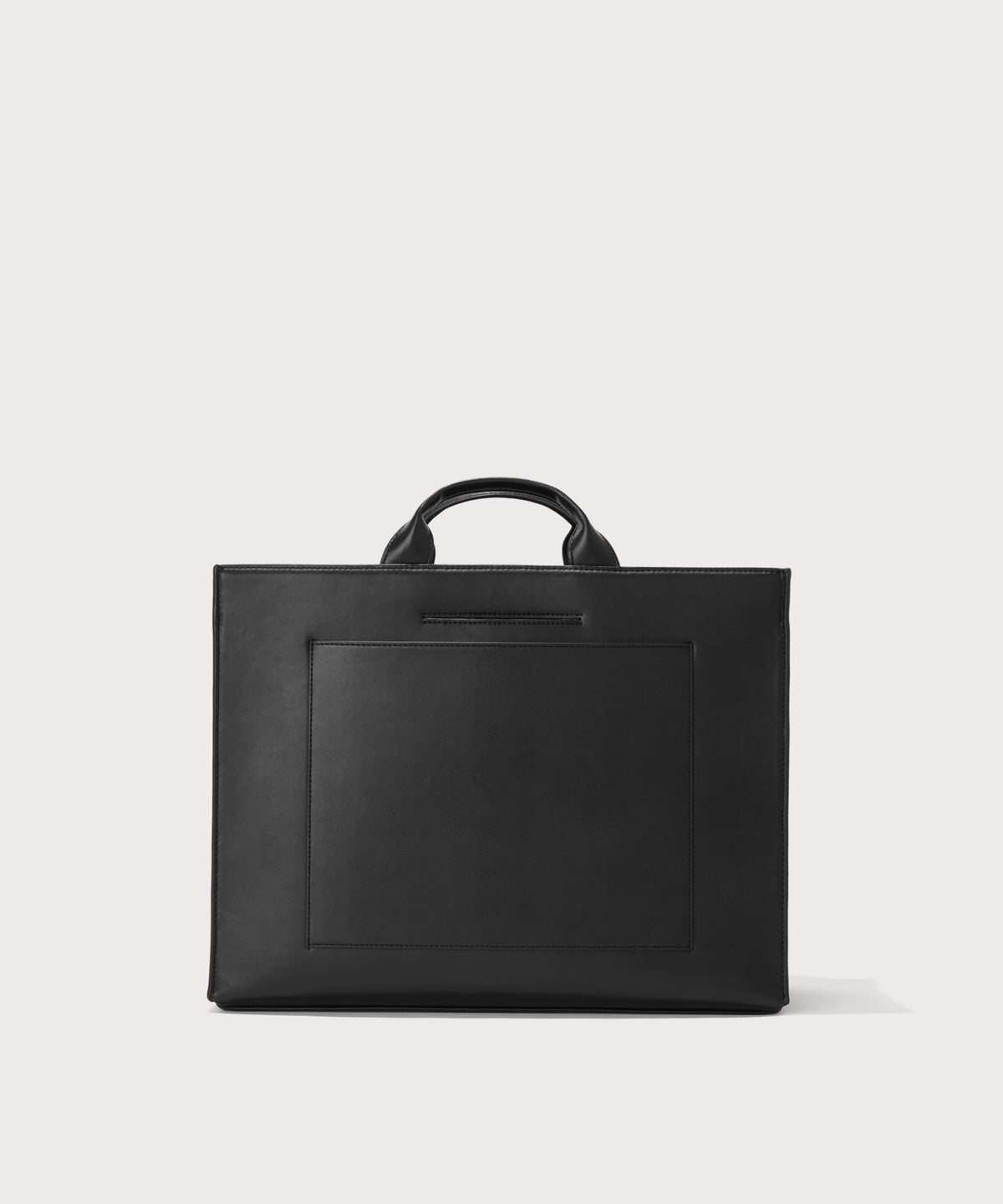 Dagne Dover large vegan Daily Tote in black revealing the exterior phone pocket and exterior luggage sleeve.
