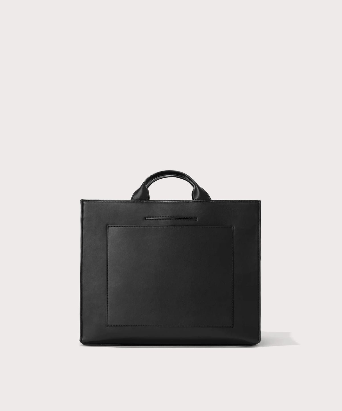Dagne Dover medium vegan Daily Tote in black revealing the exterior phone pocket and exterior luggage sleeve.