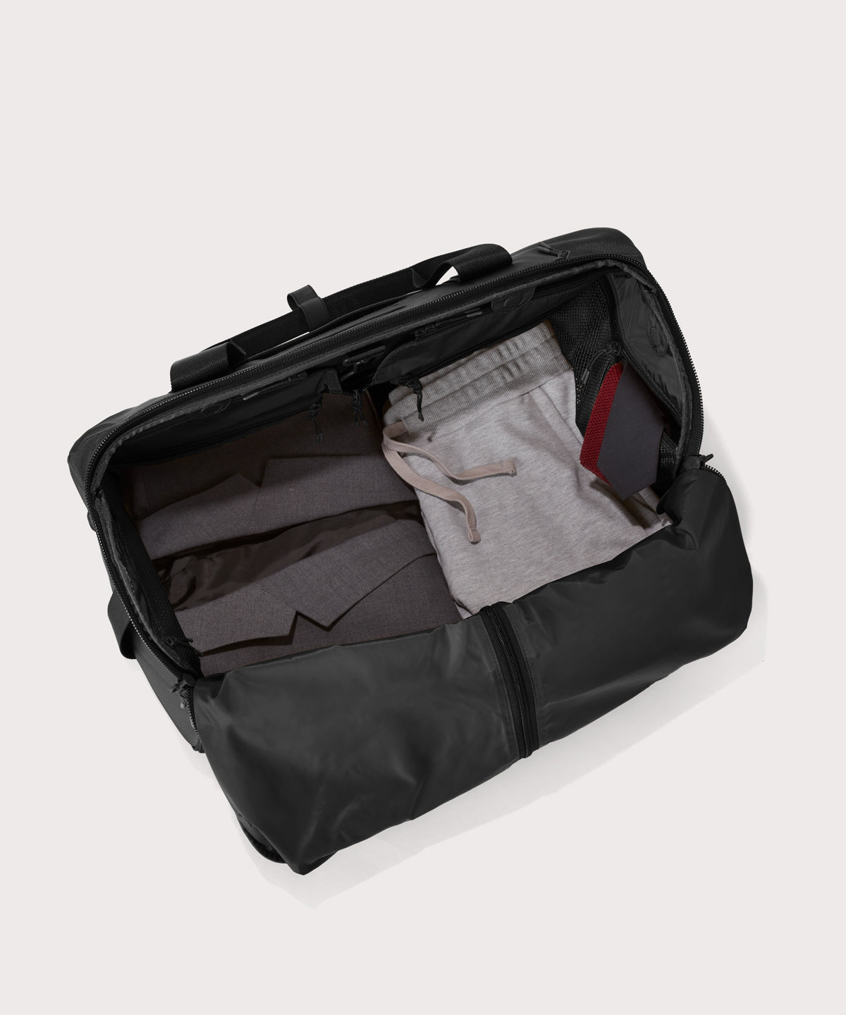 Top down of Monaco garment duffle in black with packing cube on the right side.
