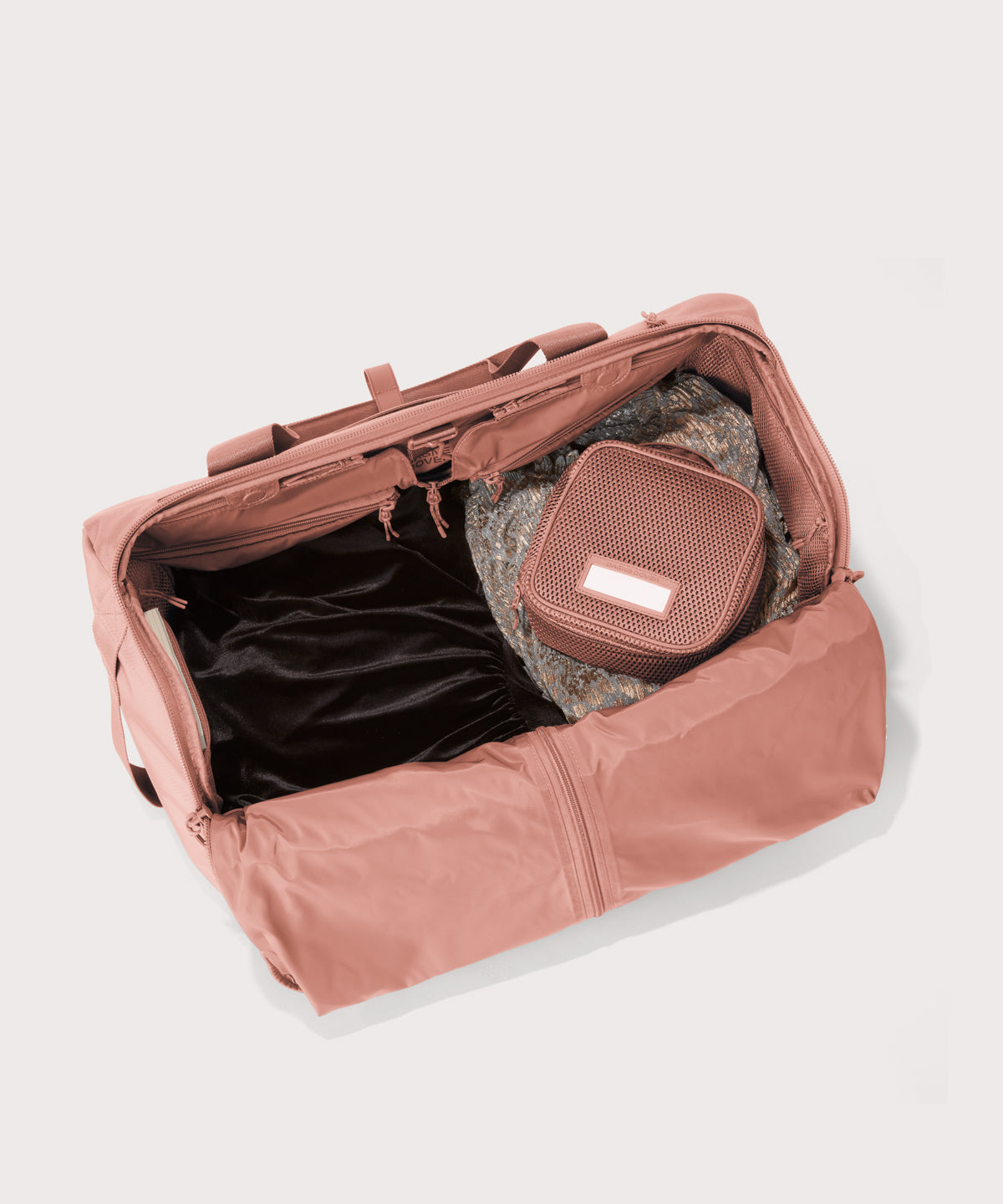 Top down of Monaco garment duffle in warm dust with packing cube on the right side.
