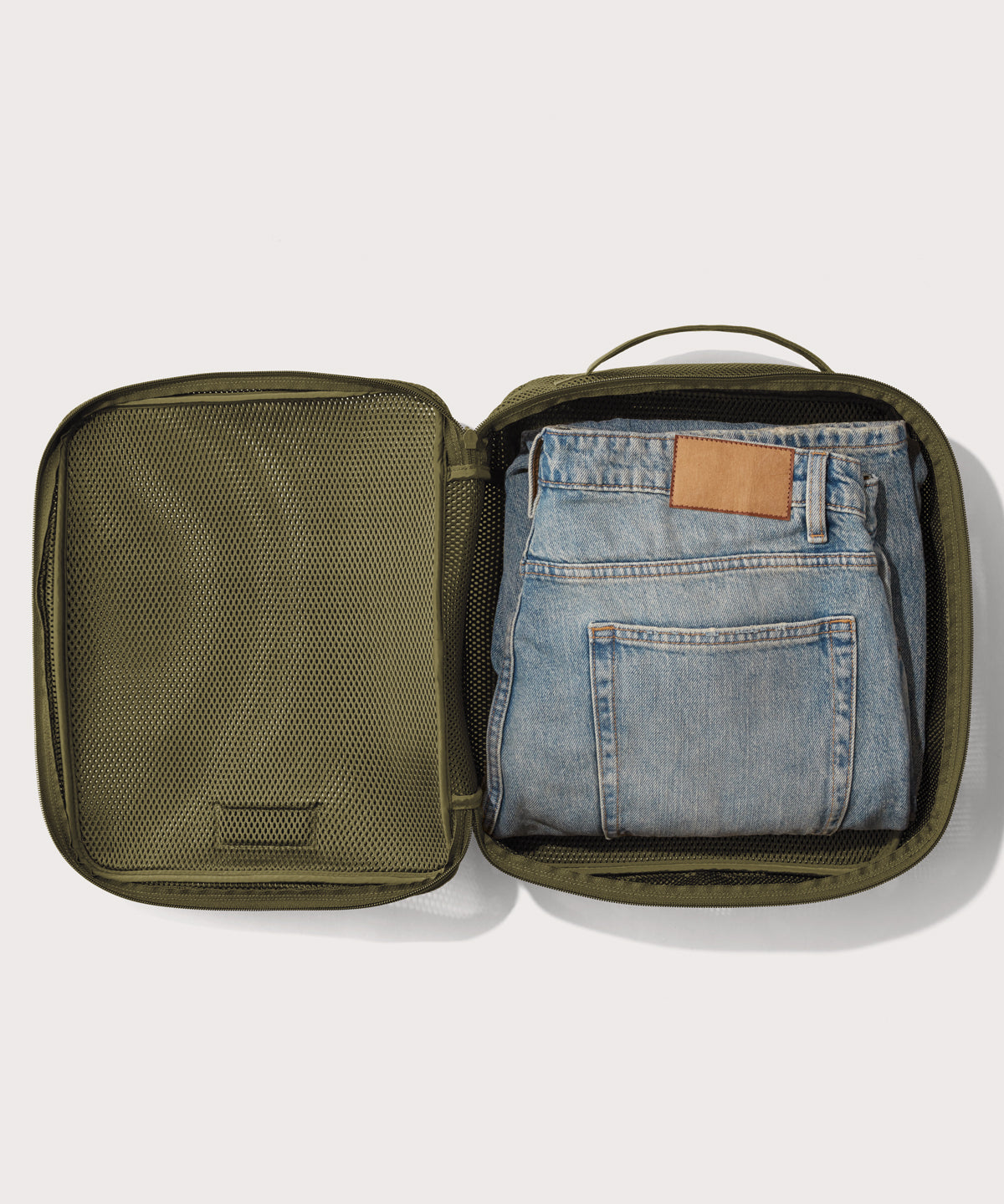 Large Roma packing cube in dark green open with jeans inside
