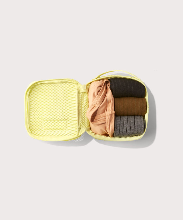 small Roma packing cube in citrine open with jeans inside
