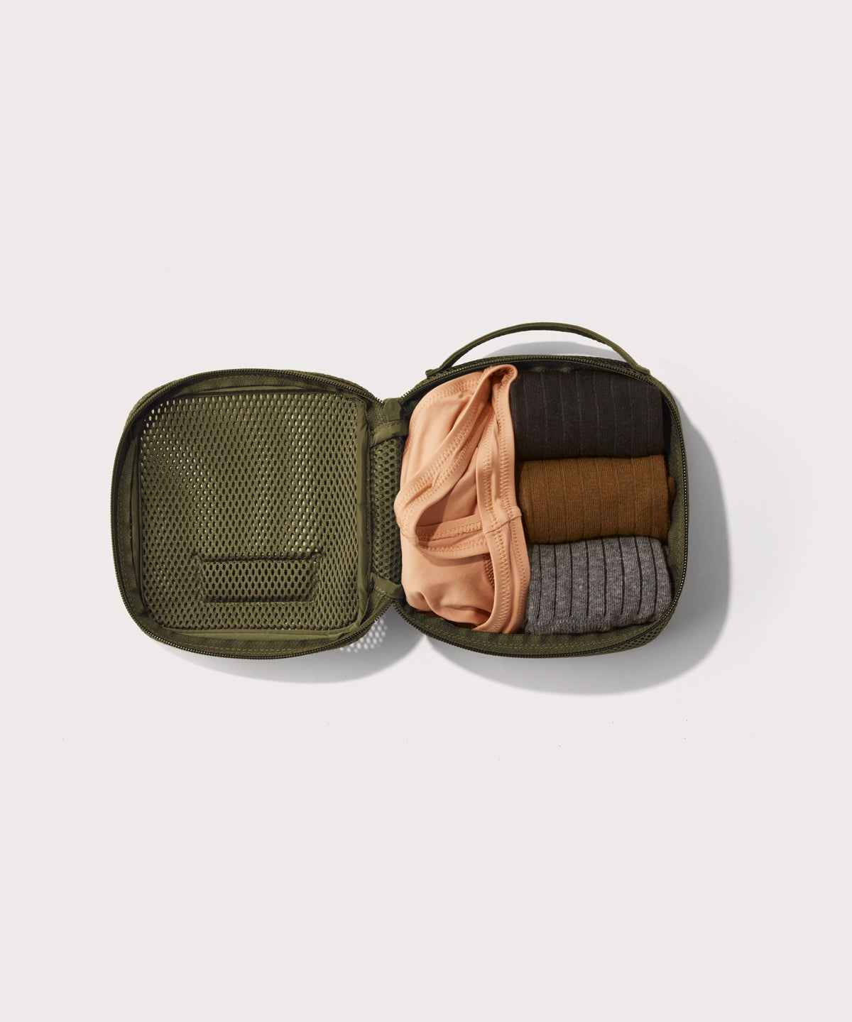 small Roma packing cube in dark green open with jeans inside
