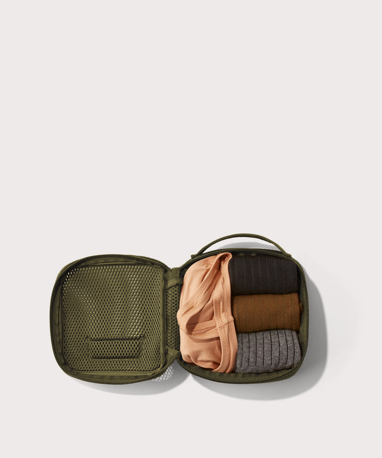 small Roma packing cube in dark green open with jeans inside