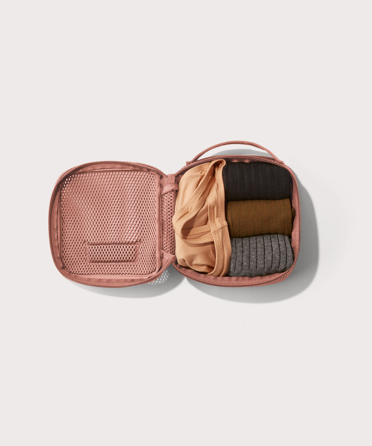 small Roma packing cube in warm dust pink open with jeans inside
