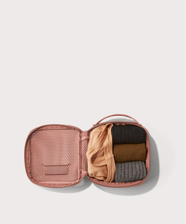 small Roma packing cube in warm dust pink open with jeans inside
