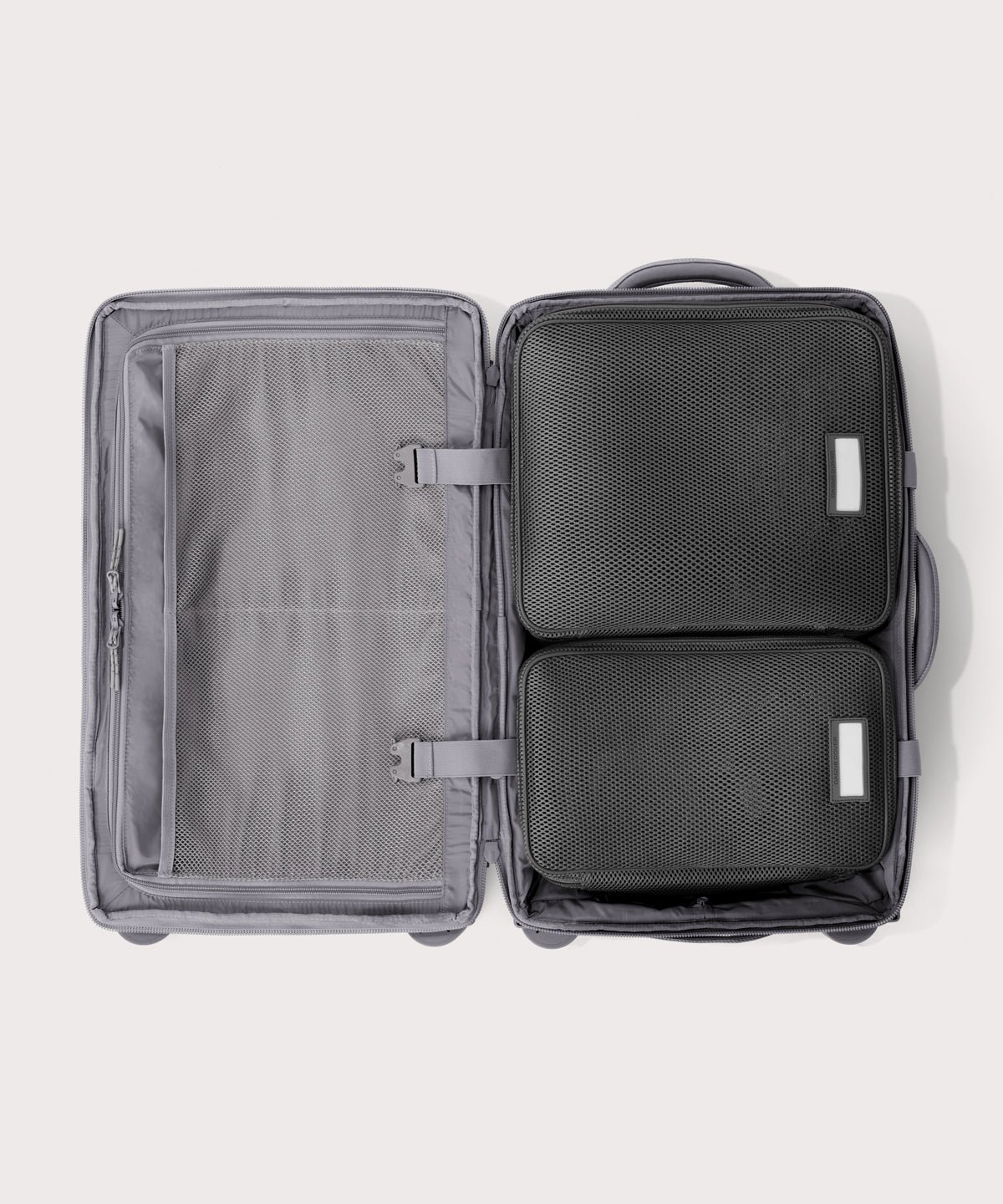 Top down of Seattle carry-on rolling luggage 20.5” in light grey with interior divider zipped and packing cubes packed into the right side. 

