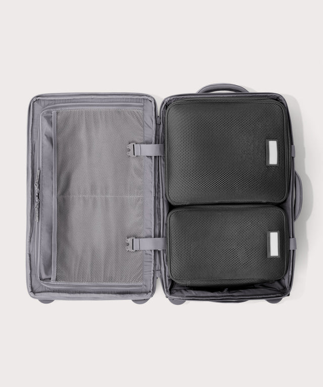 Top down of Seattle carry-on rolling luggage 20.5” in light grey with interior divider zipped and packing cubes packed into the right side. 
