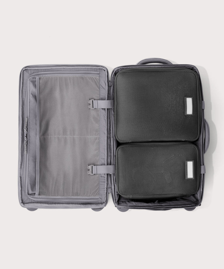 Top down of Seattle carry-on rolling luggage 20.5” in light grey with interior divider zipped and packing cubes packed into the right side. 
