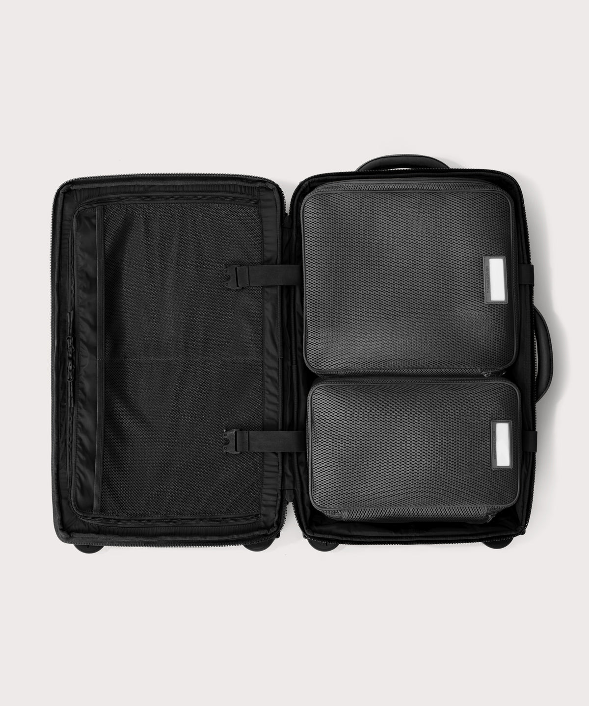 Top down of Seattle carry-on rolling luggage 23.5” in onyx with interior divider zipped and packing cubes packed into the right side.
