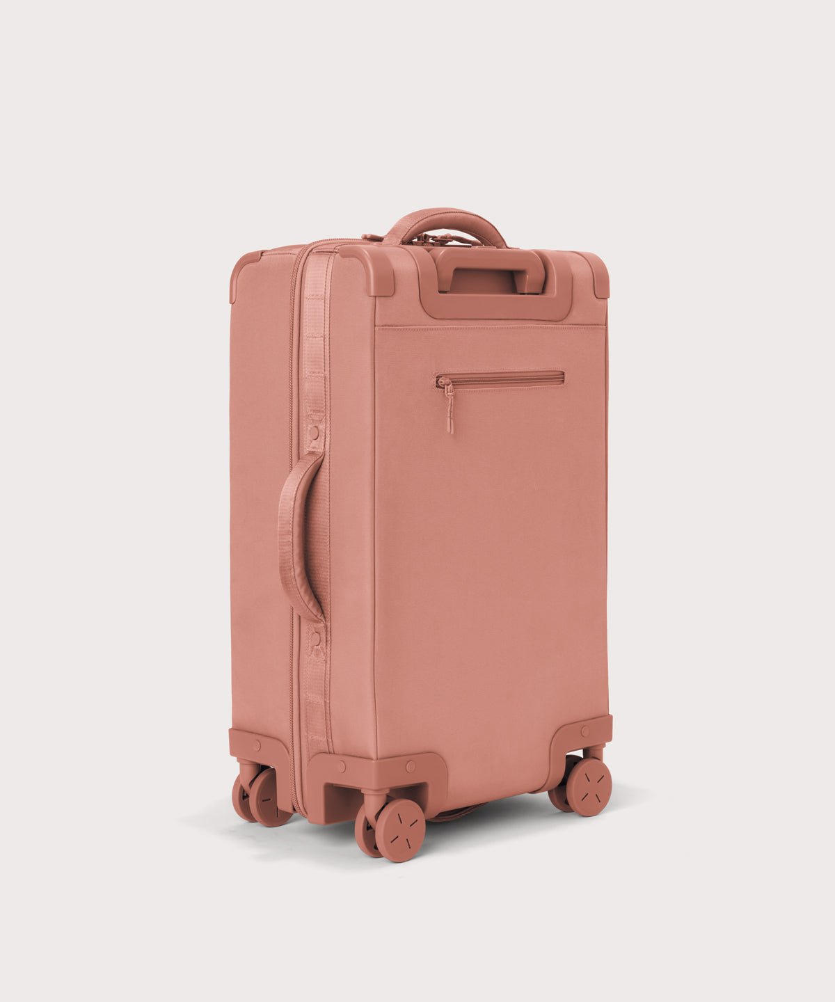 3/4 back view of Seattle carry-on rolling luggage 20.5” in warm dust pink showing side handle and back zippered phone/passport pocket
