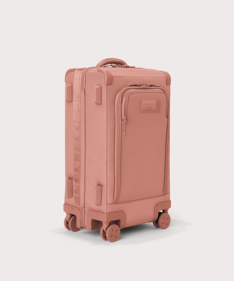 3/4 front view of Seattle carry-on rolling luggage 20.5” in warm dust pink showing side luggage feet
