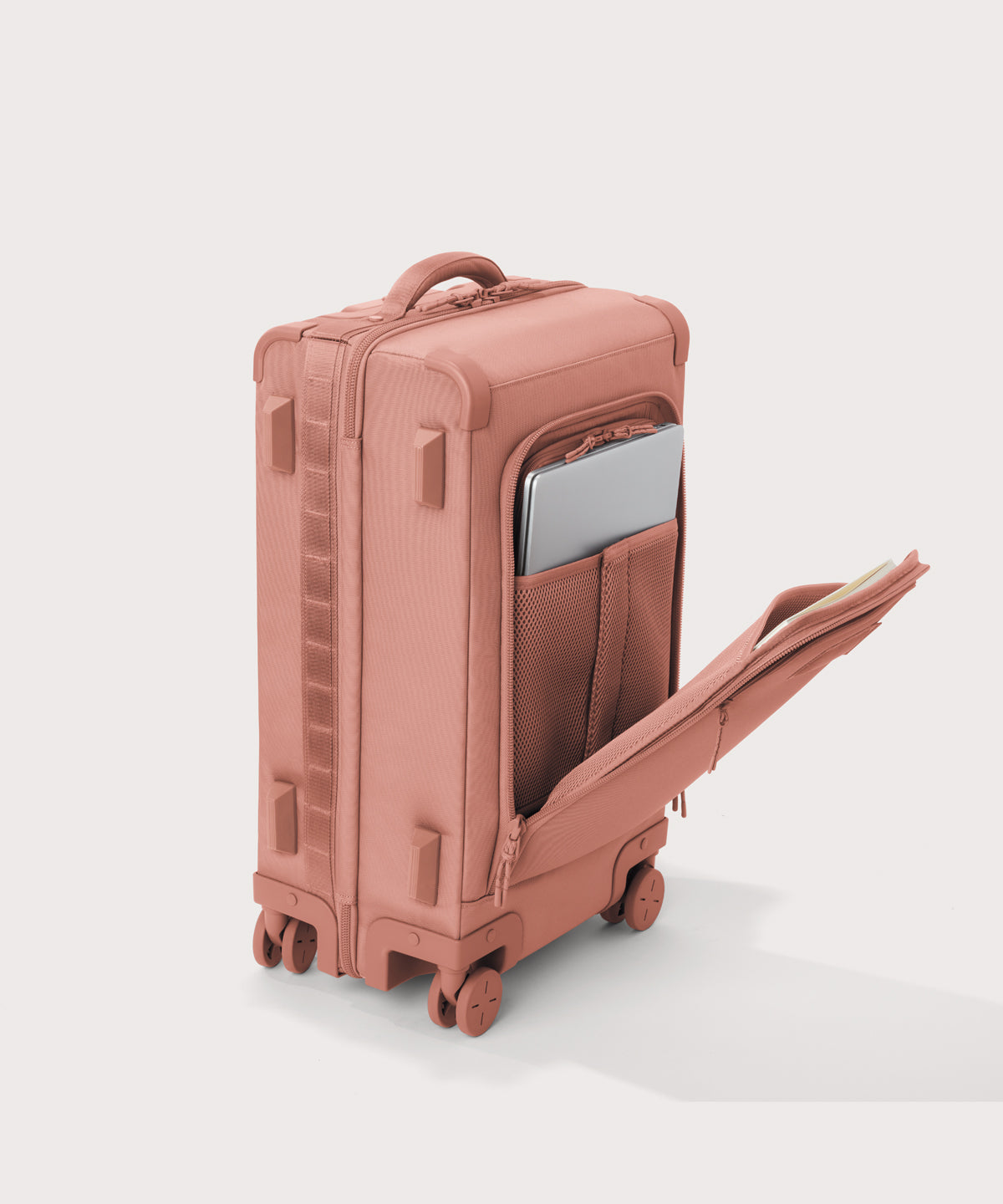 ¾ front view of Seattle carry-on rolling luggage 23.5” in warm dust pink with front flap opened. Caption: Interior slip pocket fits most 16" laptops
