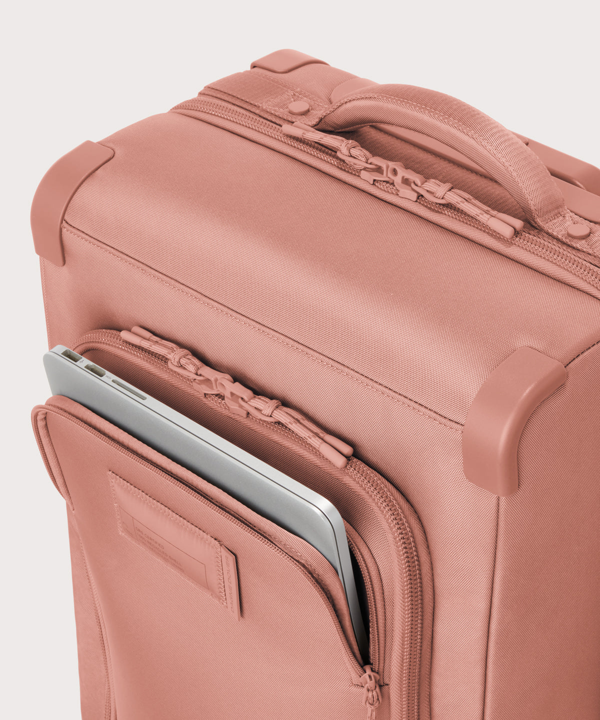 Top down of Seattle carry-on rolling luggage 23.5” in warm dust pink with front flap opened. 
