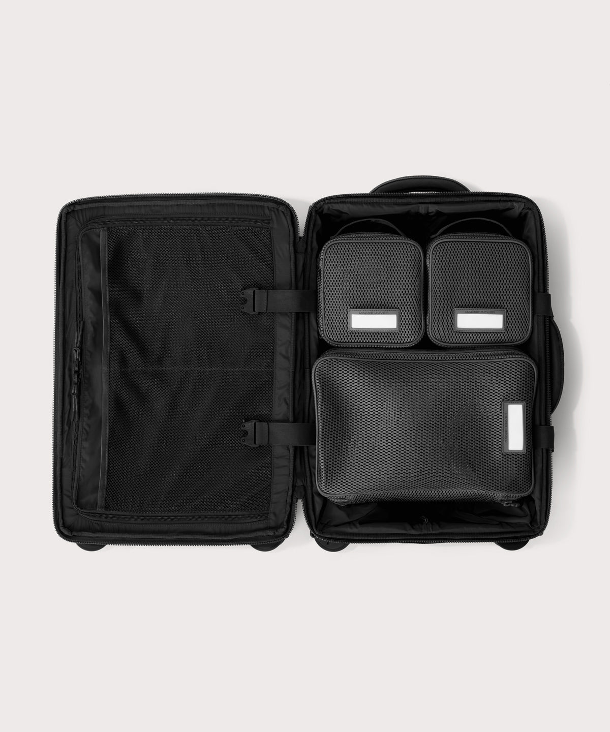 Top down of Seattle carry-on rolling luggage 20.5” in onyx with interior divider zipped and packing cubes packed into the right side. 
