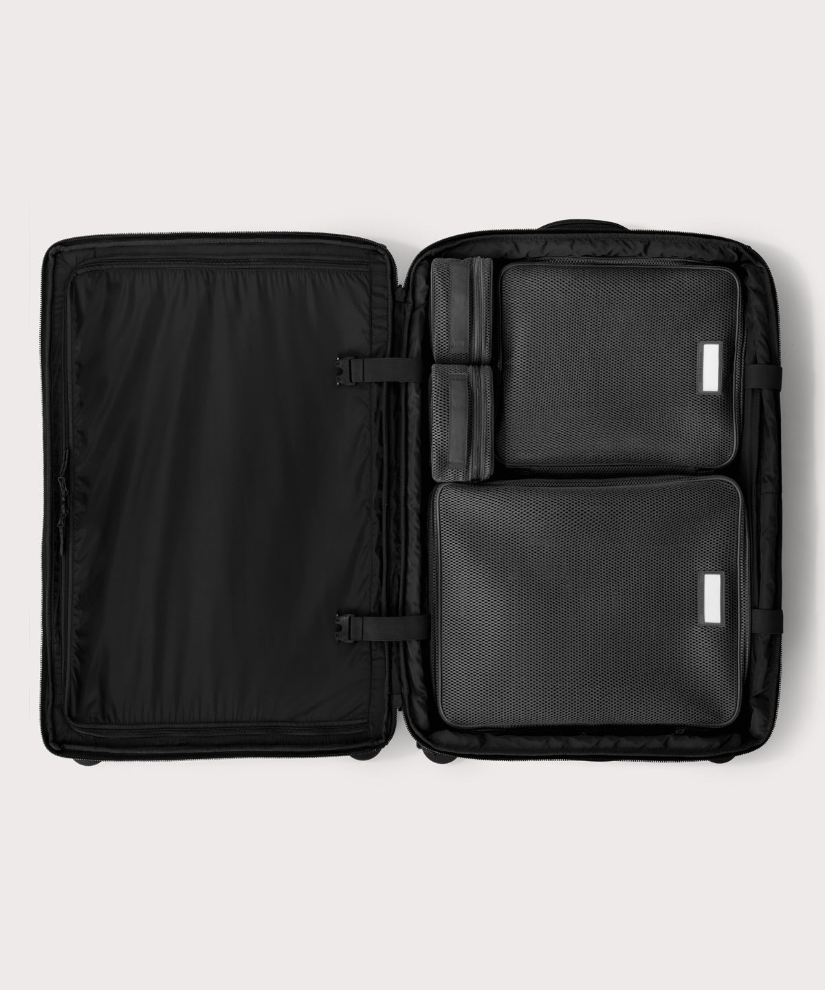 Top down of Sydney checked rolling luggage 28.5” in onyx with interior divider zipped and packing cubes packed into the right side. 

