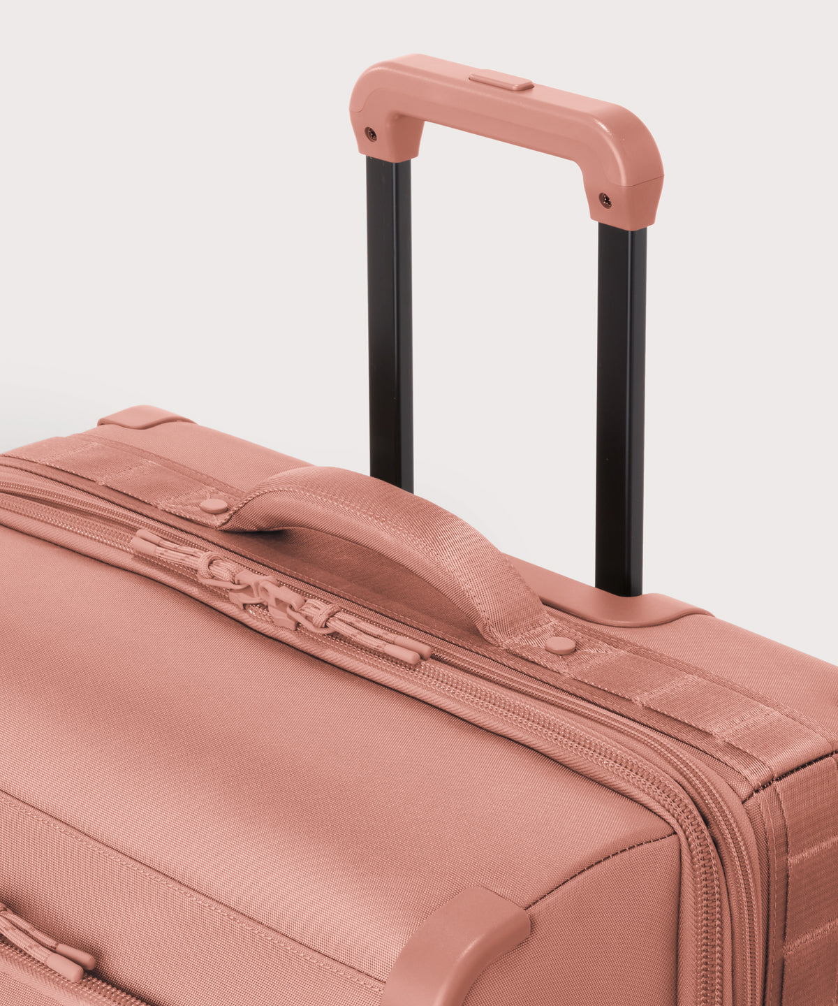 Detail shot of Sydney checked rolling luggage 25" in warm dust pink extended luggage handle and puffy handle