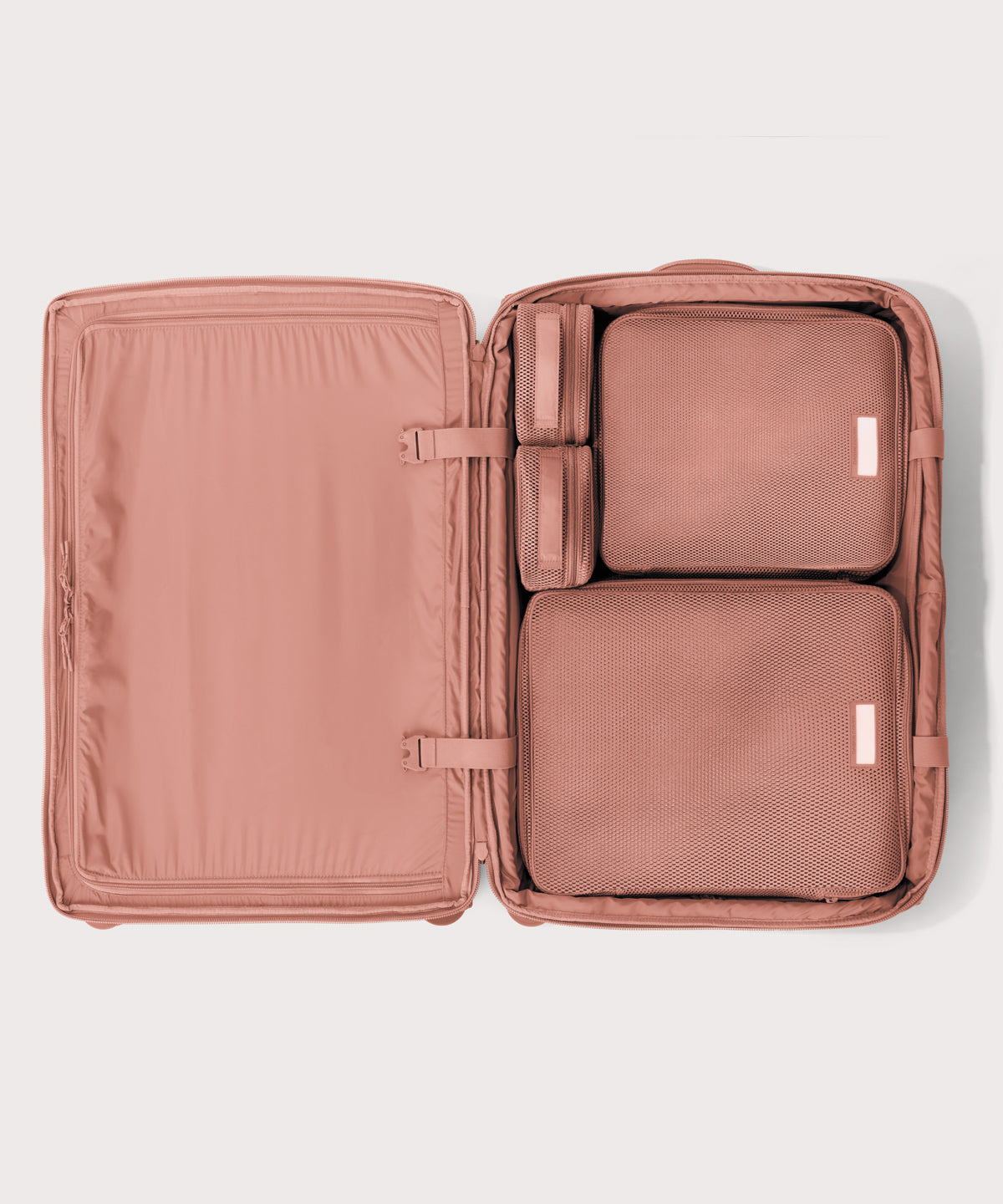 Top down of Sydney checked rolling luggage 28.5” in warm dust pink with interior divider zipped and packing cubes packed into the right side. 
