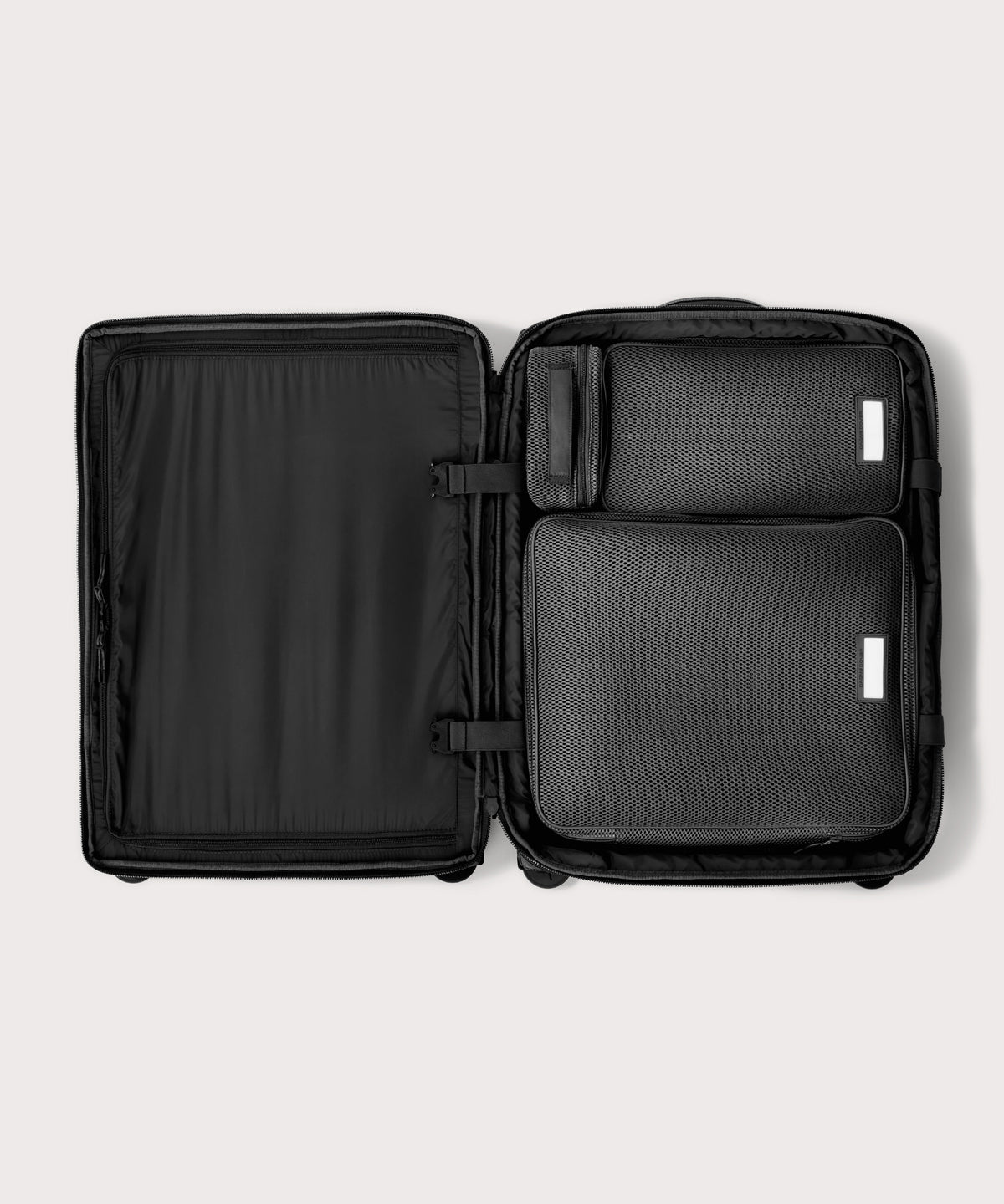 Top down of Sydney checked rolling luggage 25" in black with interior divider zipped and packing cubes packed into the right side. 
