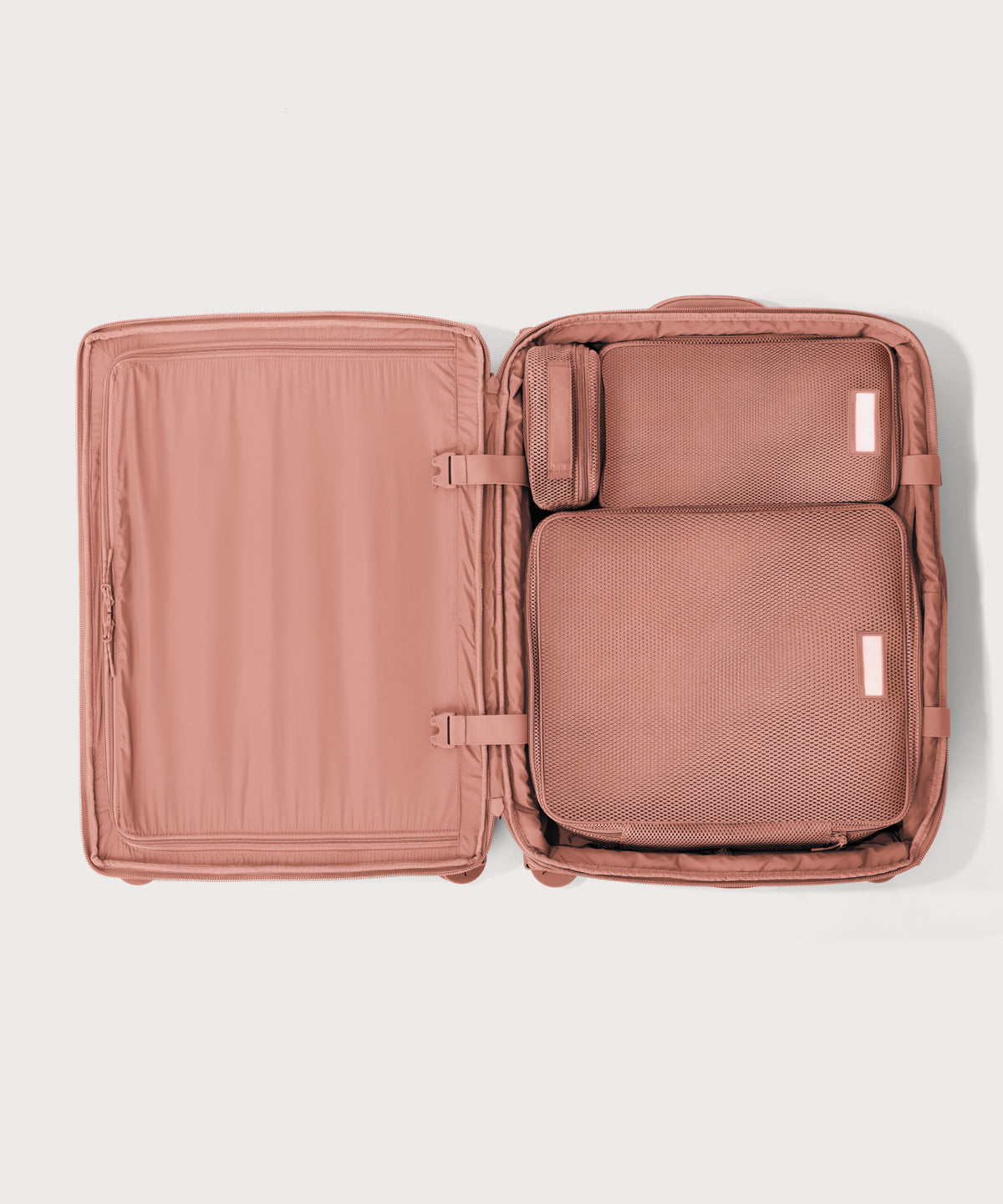 Top down of Sydney checked rolling luggage 25" in warm dust pink with interior divider zipped and packing cubes packed into the right side. 
