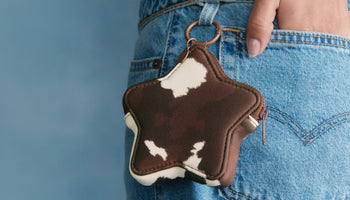 Star-shaped keychain with cowhide pattern attached to blue jeans.