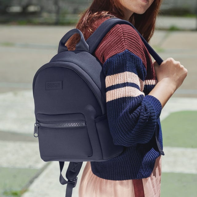 Small Dakota Backpack in navy blue being worn on one shoulder editorial image